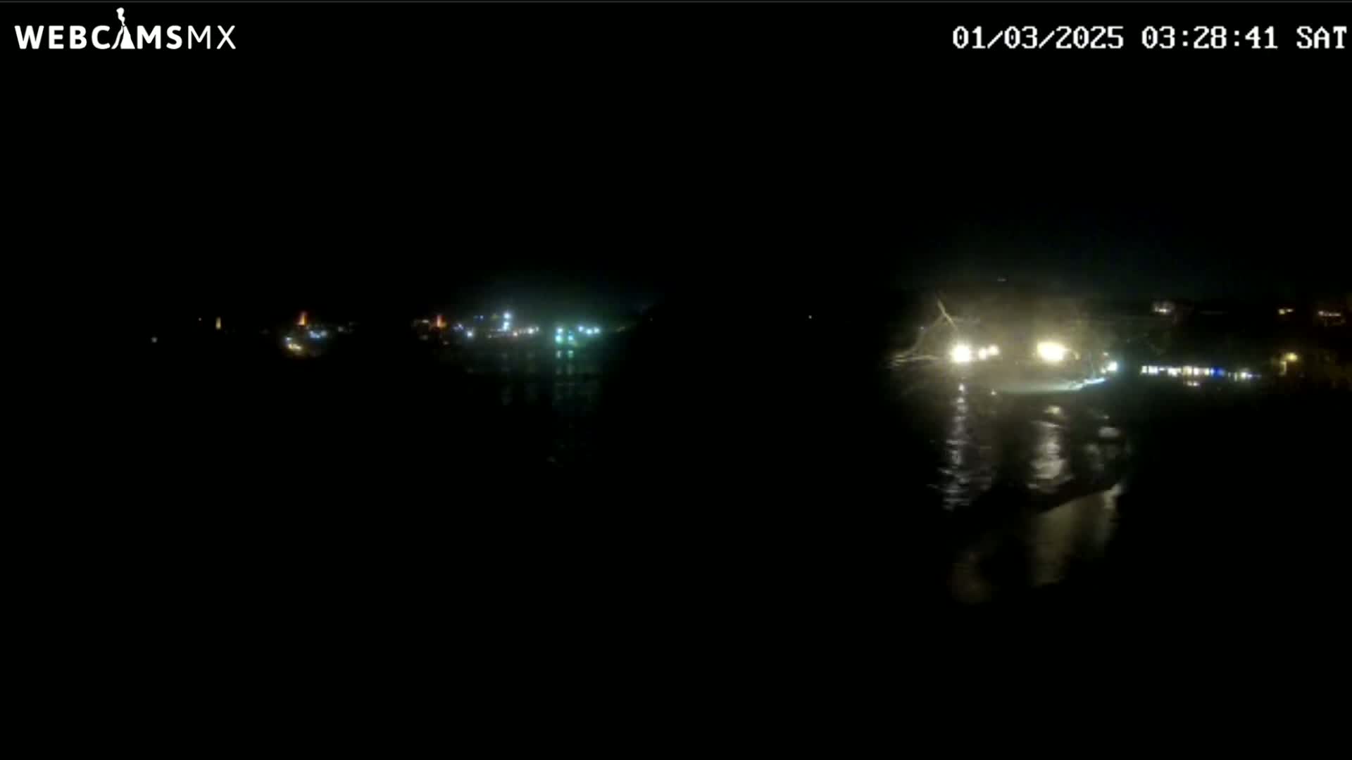 A dark nighttime scene shows distant lights across a body of water.