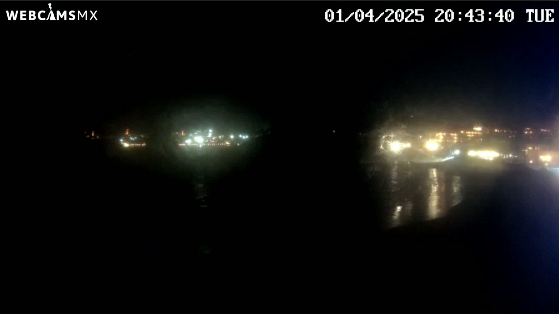 A nighttime long shot of a body of water reflecting distant lights on a dark, seemingly clear night.