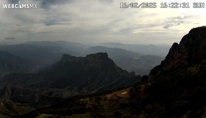 A hazy, overcast view of a vast, mountainous landscape at sunset.