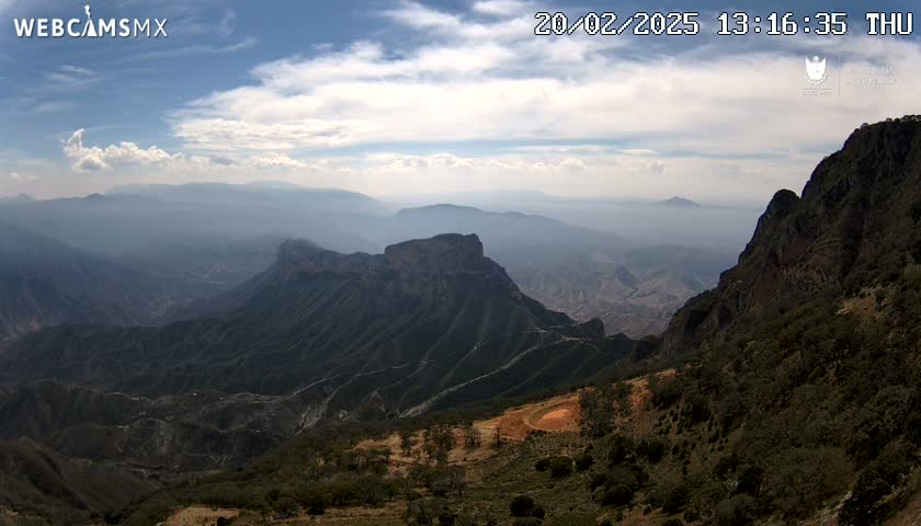 A mountain range stretches into the hazy distance under a partly cloudy sky.