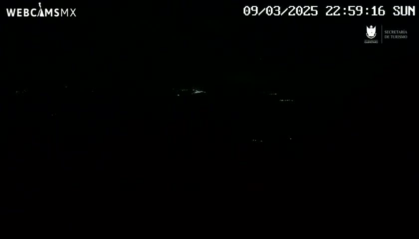A dark nighttime scene shows a few distant lights in the blackness.