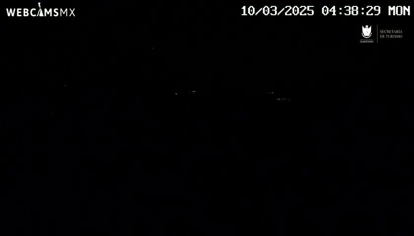 A nighttime, dark outdoor scene shows a few faint lights in the distance.