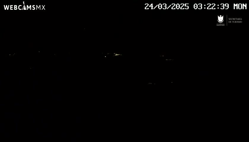 A nighttime, dark view shows scattered small lights in the distance under a clear sky.