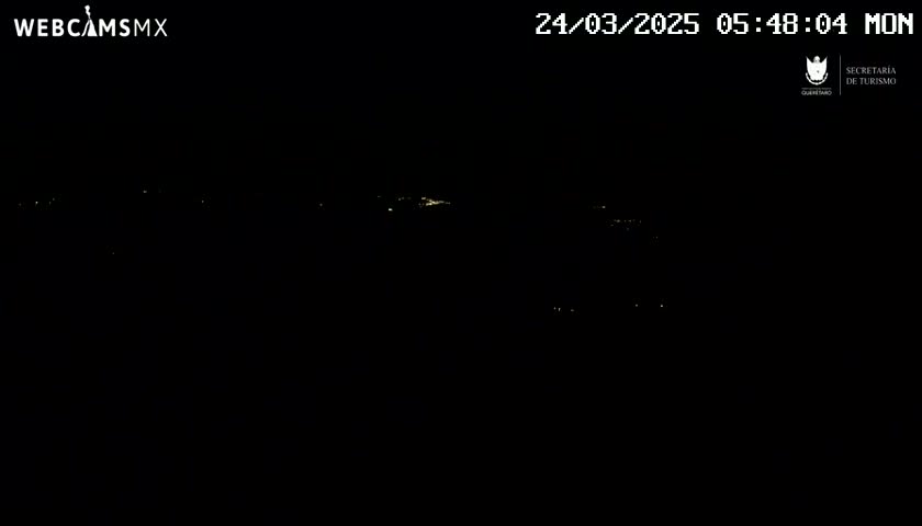 A nighttime, long shot of distant, faint lights in the darkness.