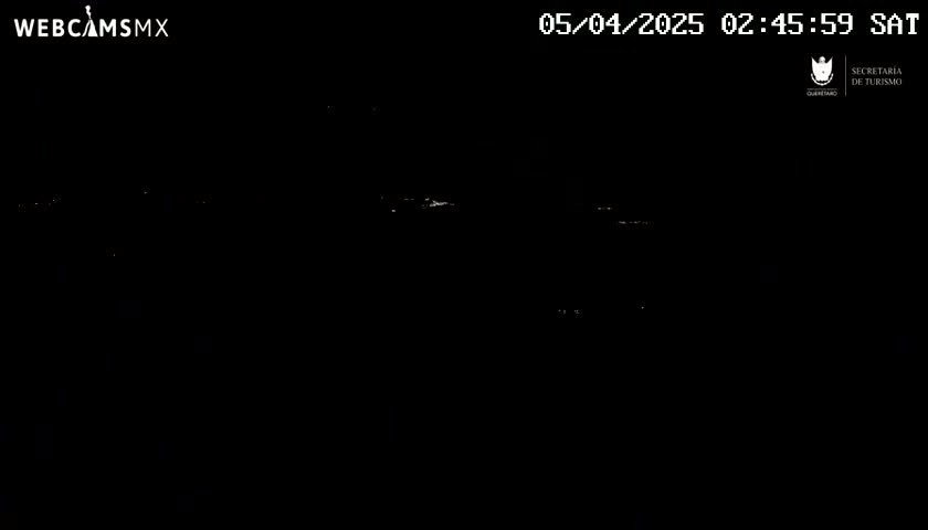 A nighttime, dark view shows distant, faint lights possibly from a town or city.