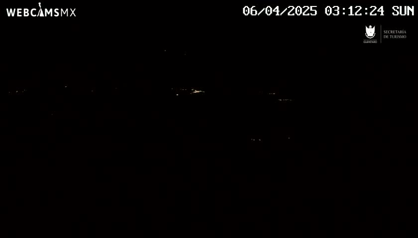 A nighttime long shot shows a dark landscape with sparsely scattered faint lights in the distance under a clear sky.