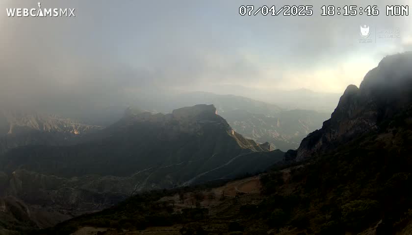 A hazy, mountainous landscape is visible at sunset.