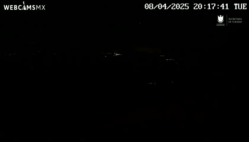 A nighttime, dark view shows a few faint lights in the distance.