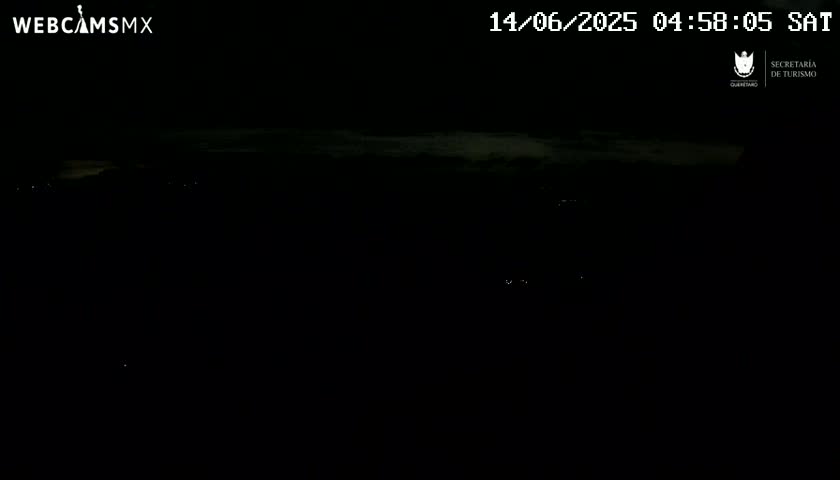 A dark, nighttime scene shows a few distant lights against a mostly overcast sky.