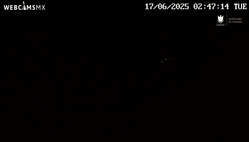A nighttime image shows a few distant, faint lights in an otherwise completely dark scene.