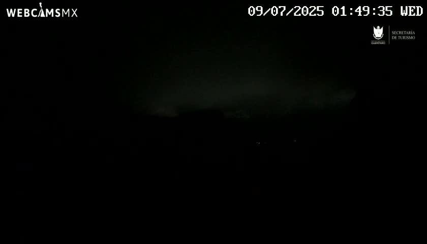 A dark, nighttime outdoor scene shows a hazy or cloudy sky over a dimly lit landscape.