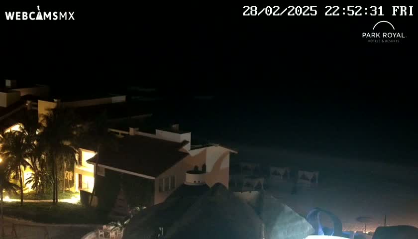 A nighttime view of a resort complex near a dark ocean under a clear sky.