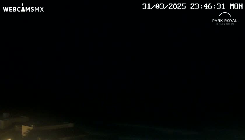 A nighttime, dark view shows a building and water in the bottom of the frame.