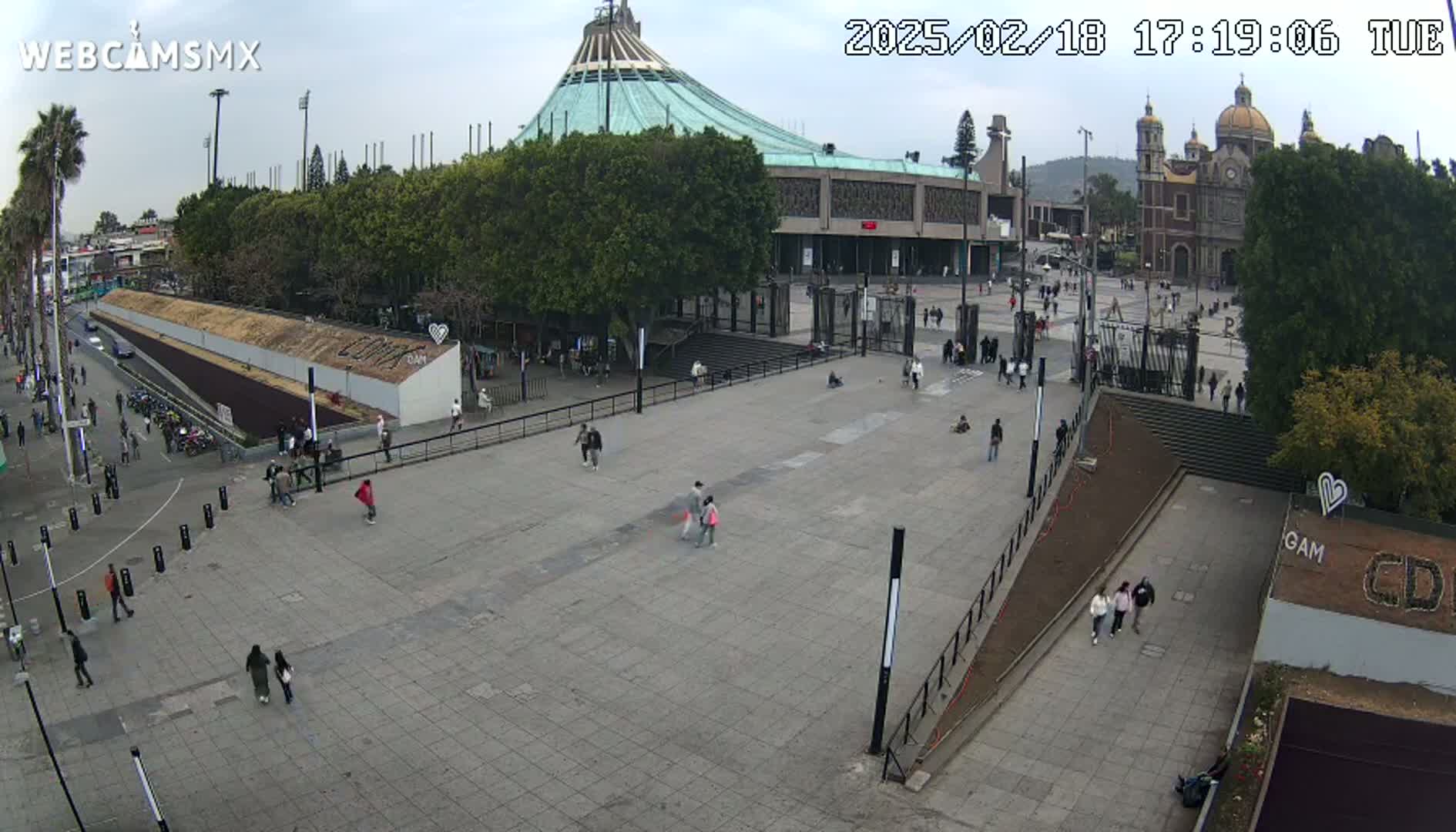 A large plaza with a few pedestrians, surrounded by buildings including a basilica, under an overcast sky.