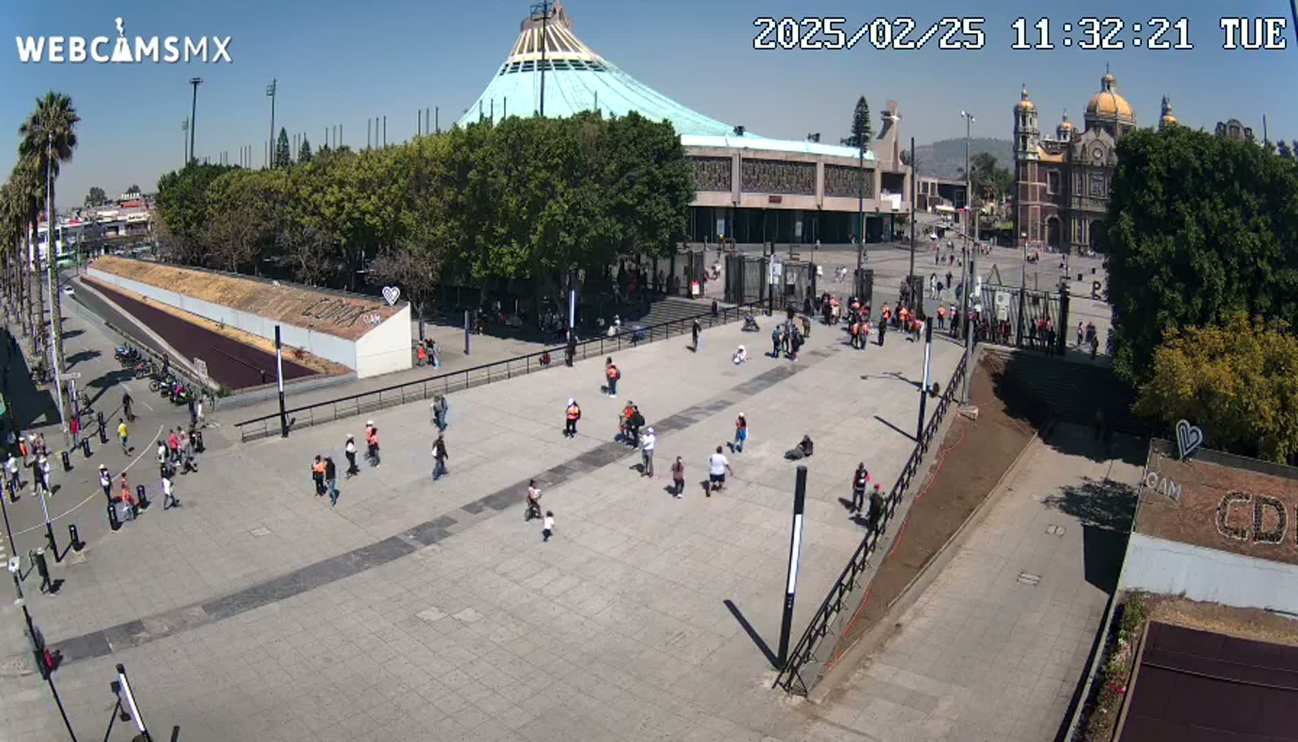 A sunny day reveals a large plaza with numerous people scattered about, in front of a large basilica and other buildings.