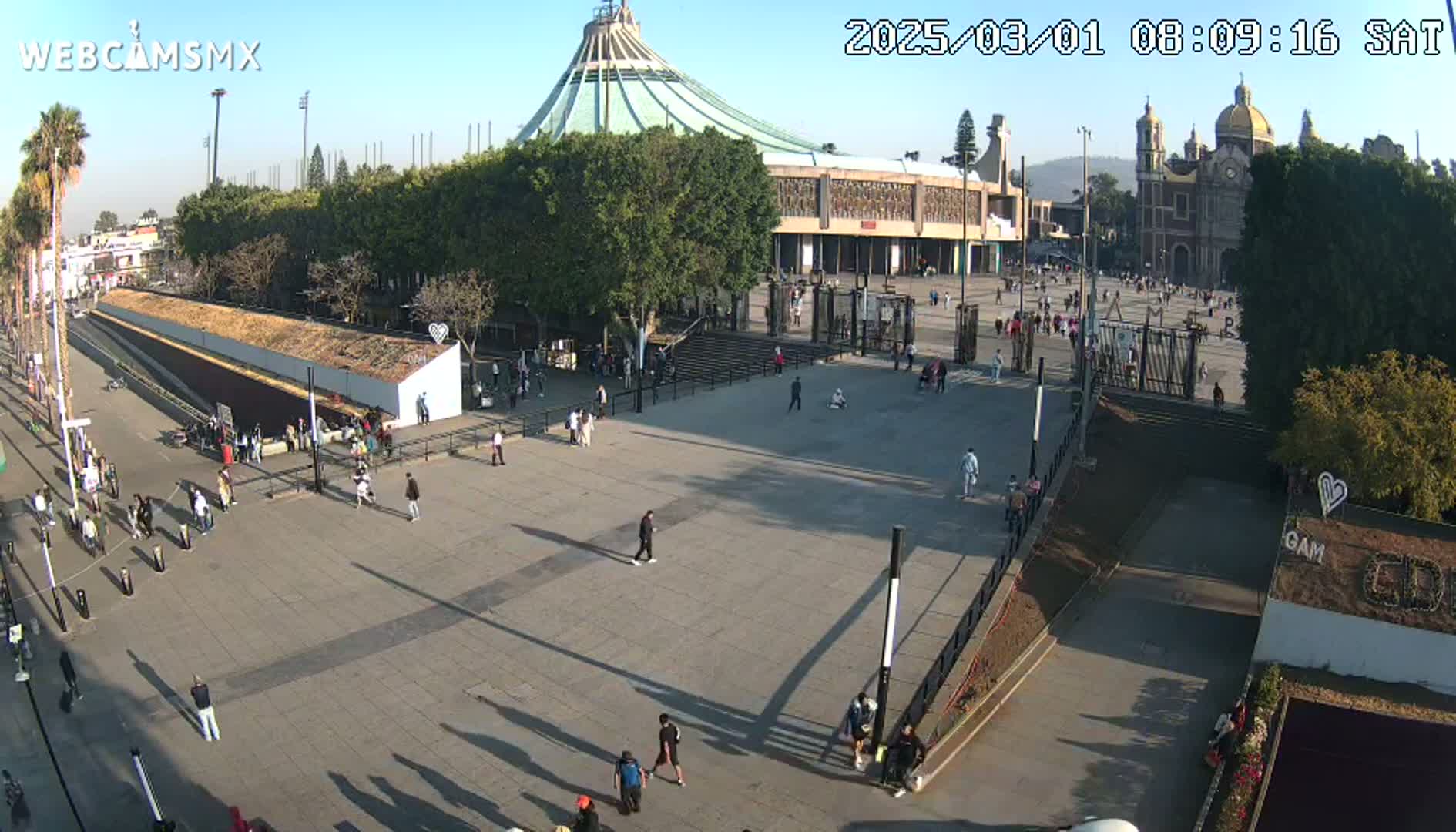 A large plaza with a basilica and several people milling about on a sunny day.