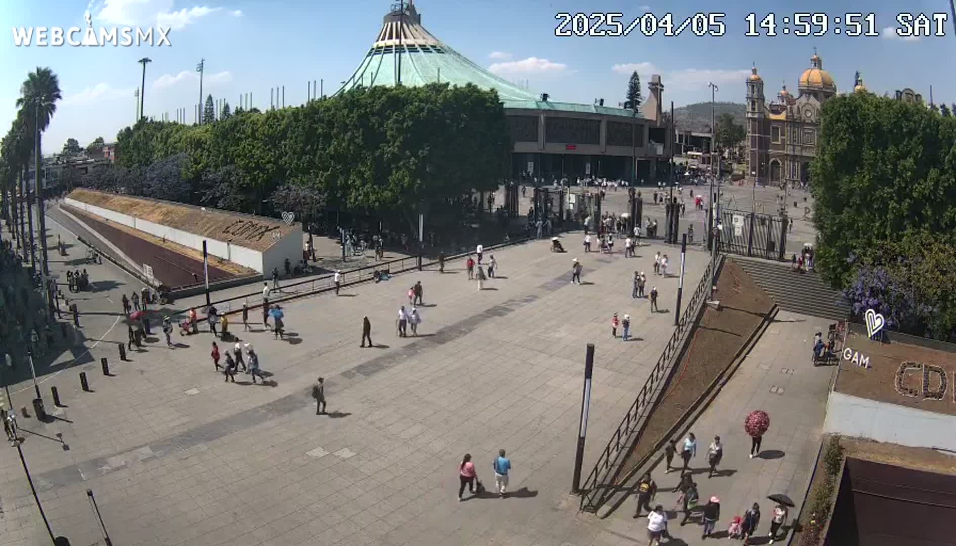 A large plaza with many people, a large basilica, and surrounding buildings under a sunny sky.