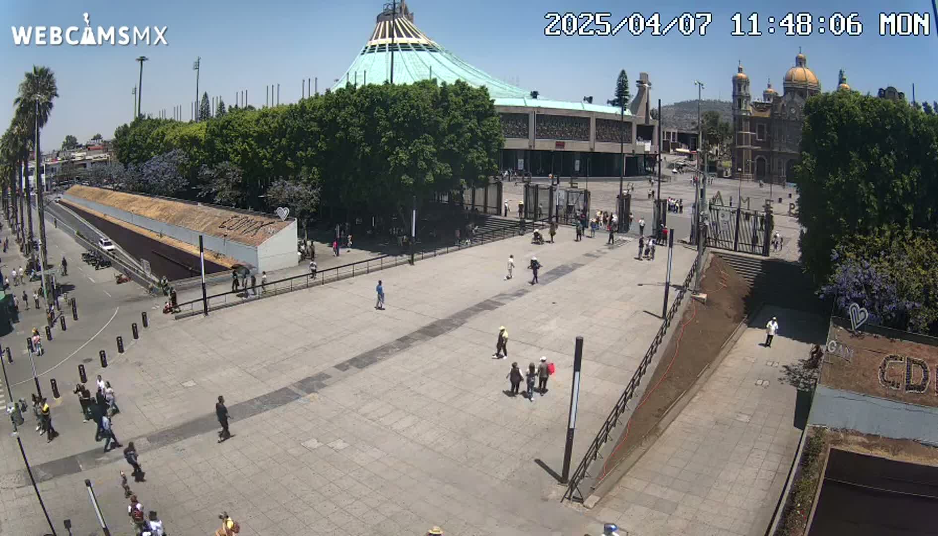 A large plaza with scattered people surrounds a basilica on a sunny day.