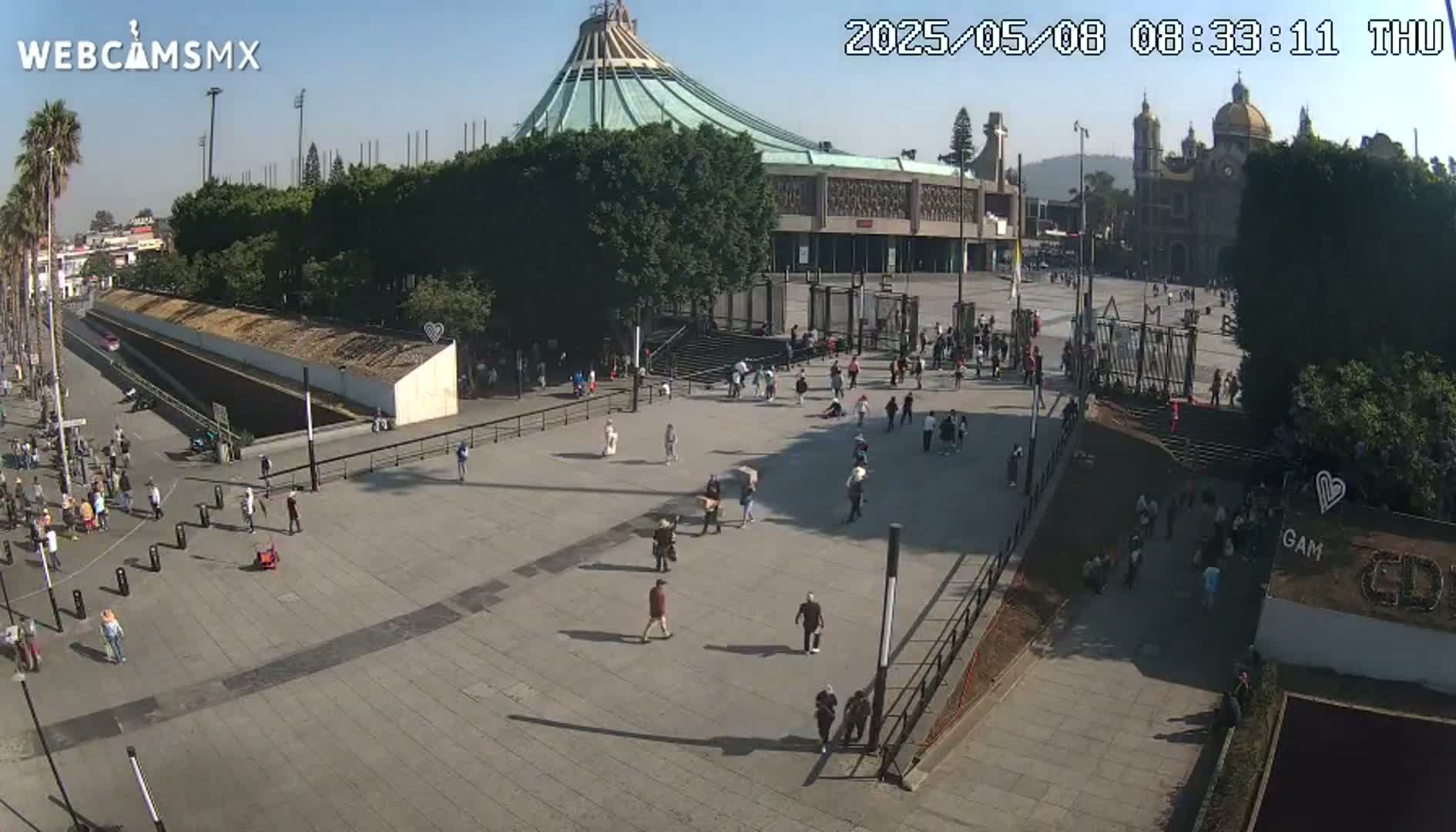 A large plaza with a basilica and many people, under a sunny sky.