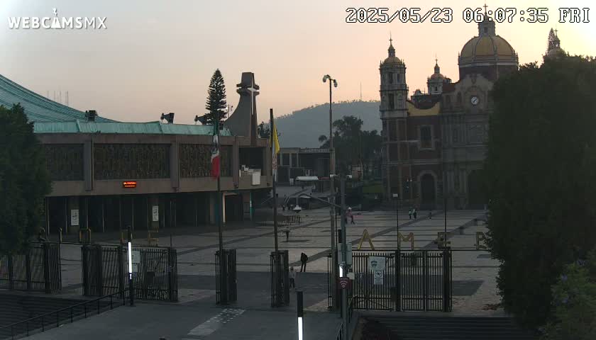 A large plaza with a basilica in the background, under a twilight sky.