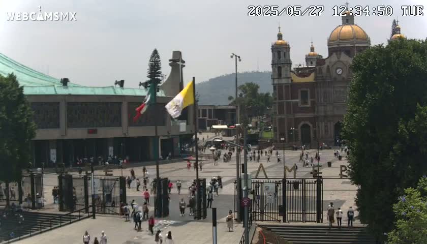 A large plaza with a crowd of people and a basilica with gold domes under a mostly clear sky.