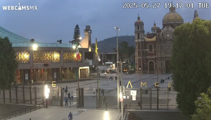 A large basilica and its plaza are visible at dusk, with a few people sparsely scattered throughout the area.