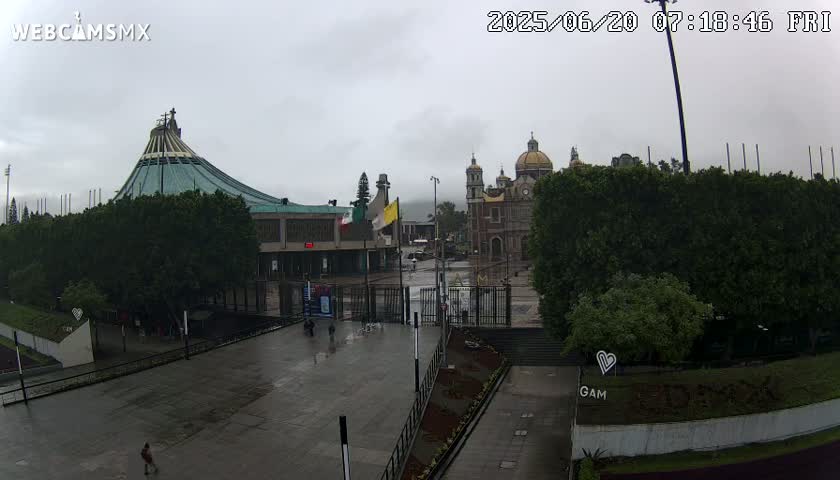 A wet plaza with two large churches sits under an overcast sky.