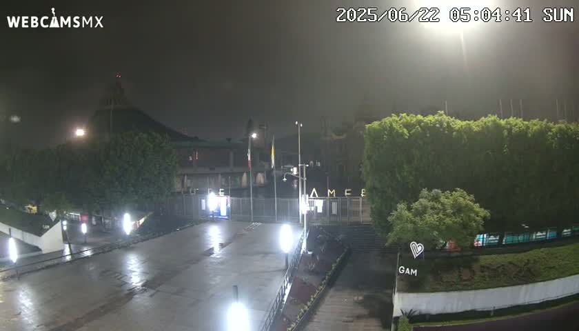 A nighttime view of a plaza and building complex, illuminated by artificial lights under hazy or foggy conditions.