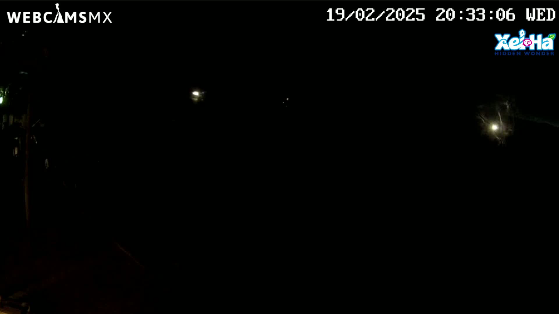 A nighttime view shows a dark scene with a few distant lights visible under a clear, dark sky.