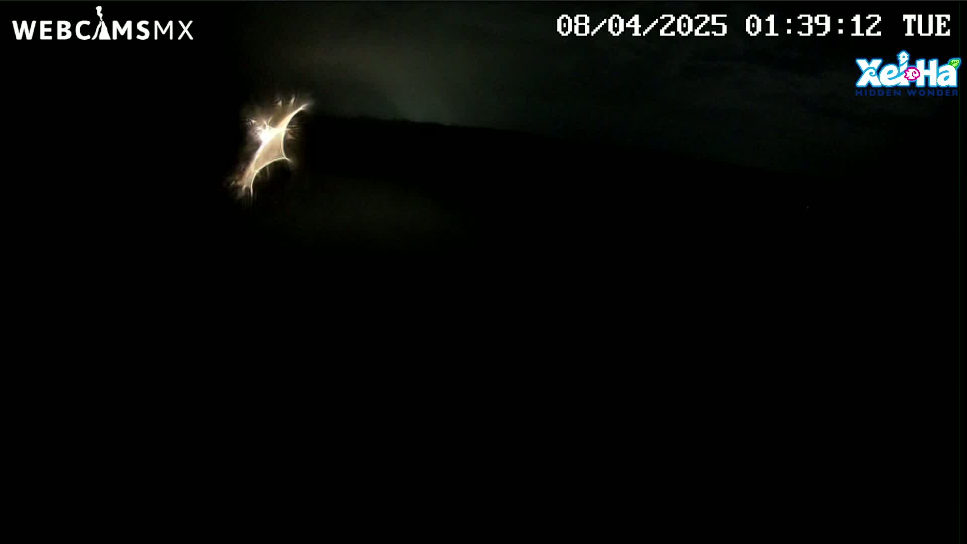 A bright, crescent-shaped light source is visible against a mostly dark, nighttime sky.