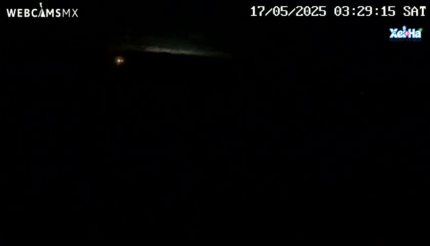 A mostly dark nighttime scene shows a faint, bright band of light in the upper portion of the image against a dark sky.