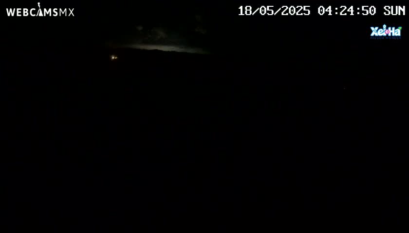 A nighttime, dark outdoor scene shows a faintly lit horizon with a few distant lights.