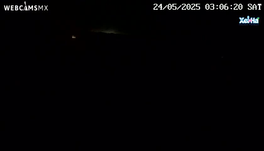 A dark, nighttime scene shows a faintly illuminated horizon under a mostly clear sky.
