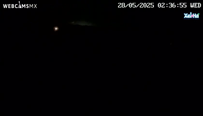 A dark, nighttime scene shows a faint, pale glow on the horizon.