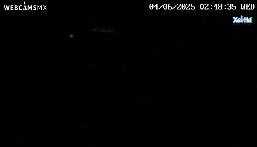 A very dark nighttime scene shows a faintly illuminated distant landscape under a mostly clear sky.