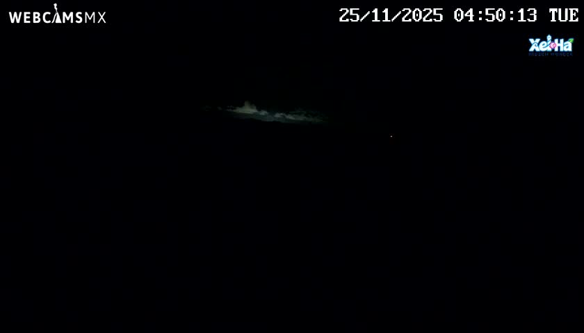 A dark night sky with partial cloud cover is visible, featuring a band of dimly lit clouds in the upper center and a faint light source to the right.