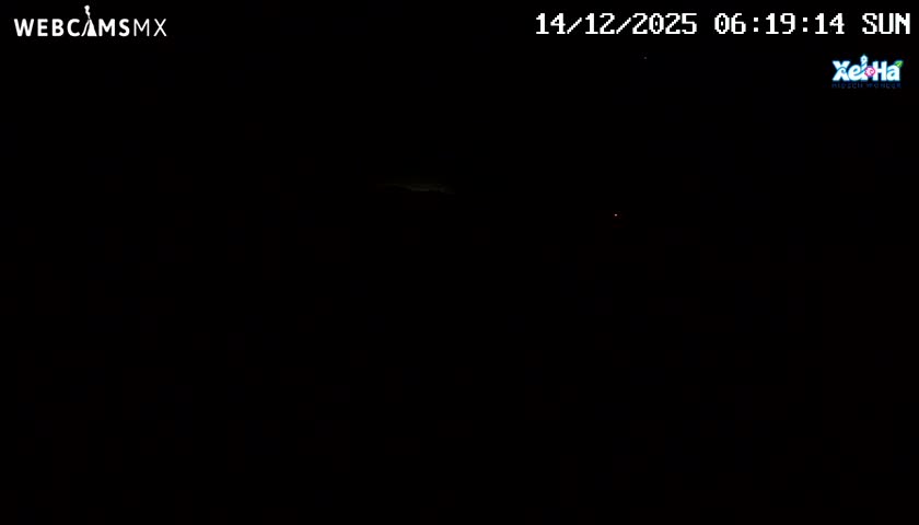 A dark night sky with partial cloud cover is visible, featuring a band of dimly lit clouds in the upper center and a faint light source to the right.