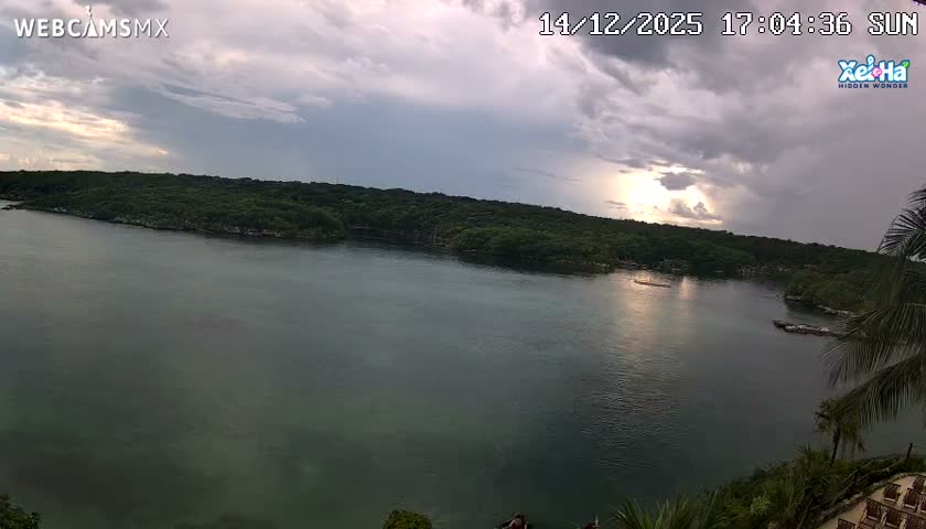 A dark night sky with partial cloud cover is visible, featuring a band of dimly lit clouds in the upper center and a faint light source to the right.