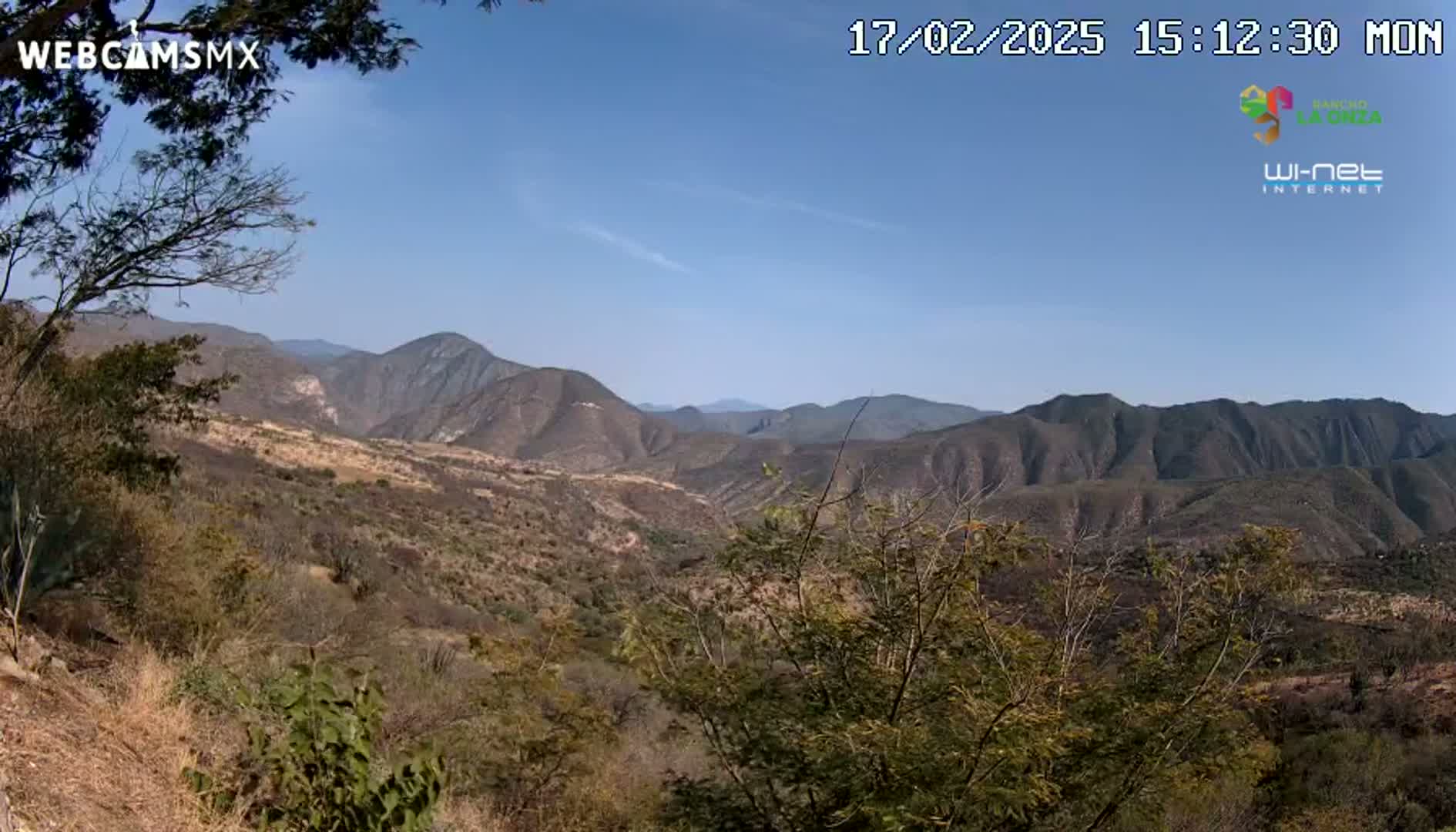 A view from a high vantage point shows a dry, mountainous landscape under a clear blue sky.