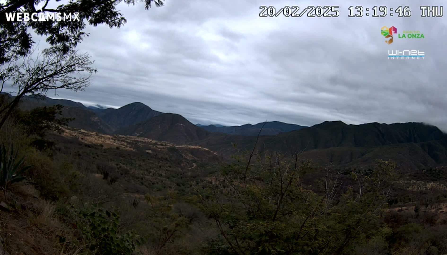 A view of a mountainous landscape under a cloudy sky, showing dark green vegetation covering the hills and valleys.