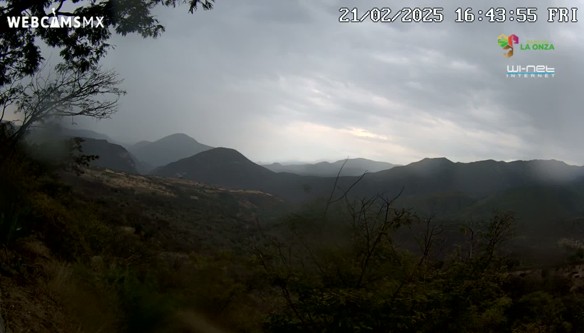 A hazy, overcast view of a mountainous landscape, with dark green vegetation covering the hillsides.
