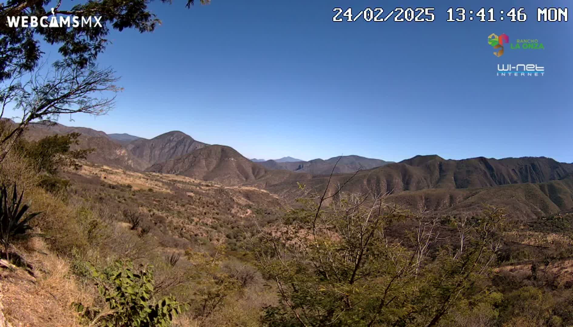 A mountainous, arid landscape is visible under a clear blue sky.