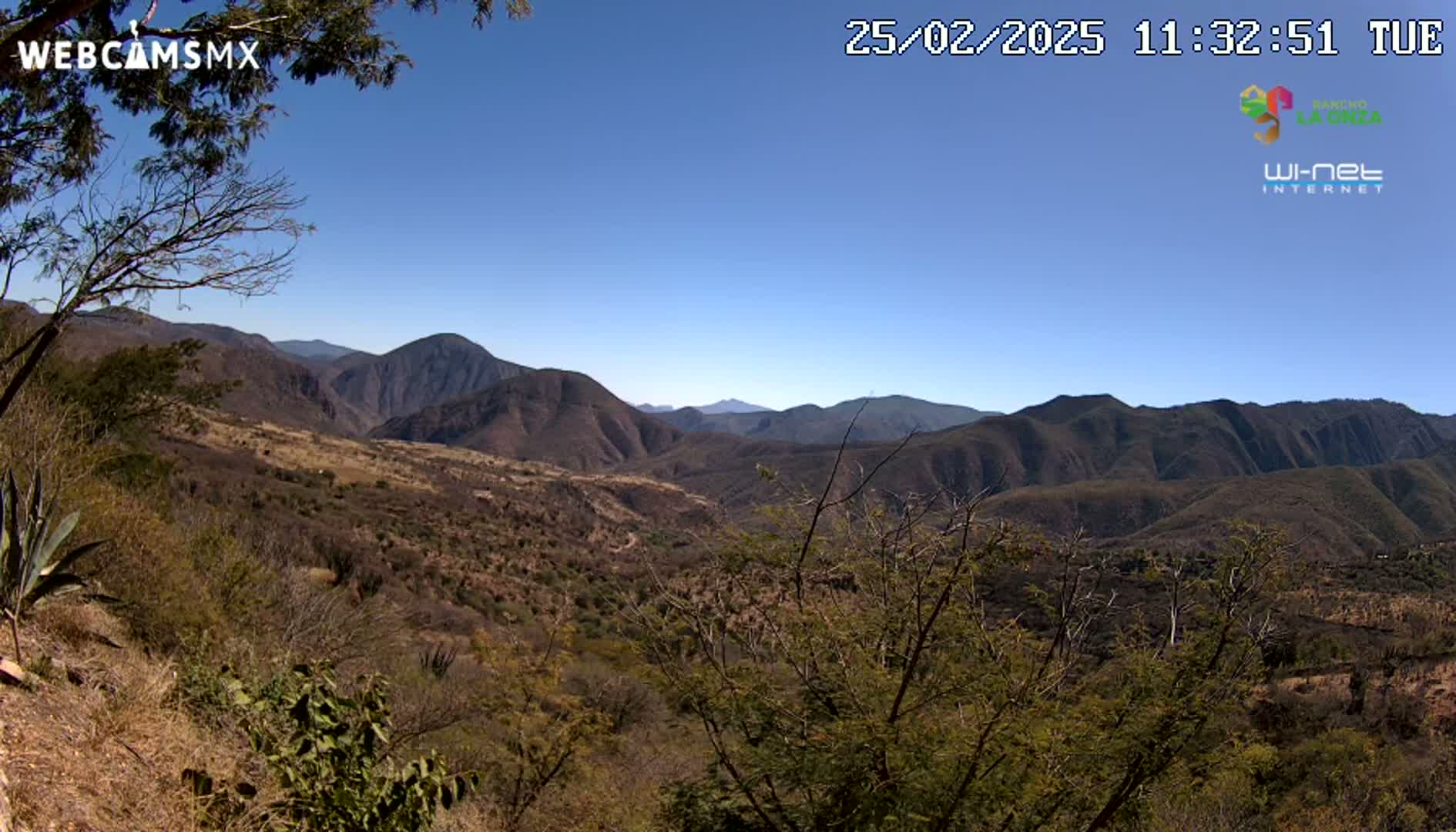 A panoramic view of a dry, mountainous landscape under a clear blue sky.