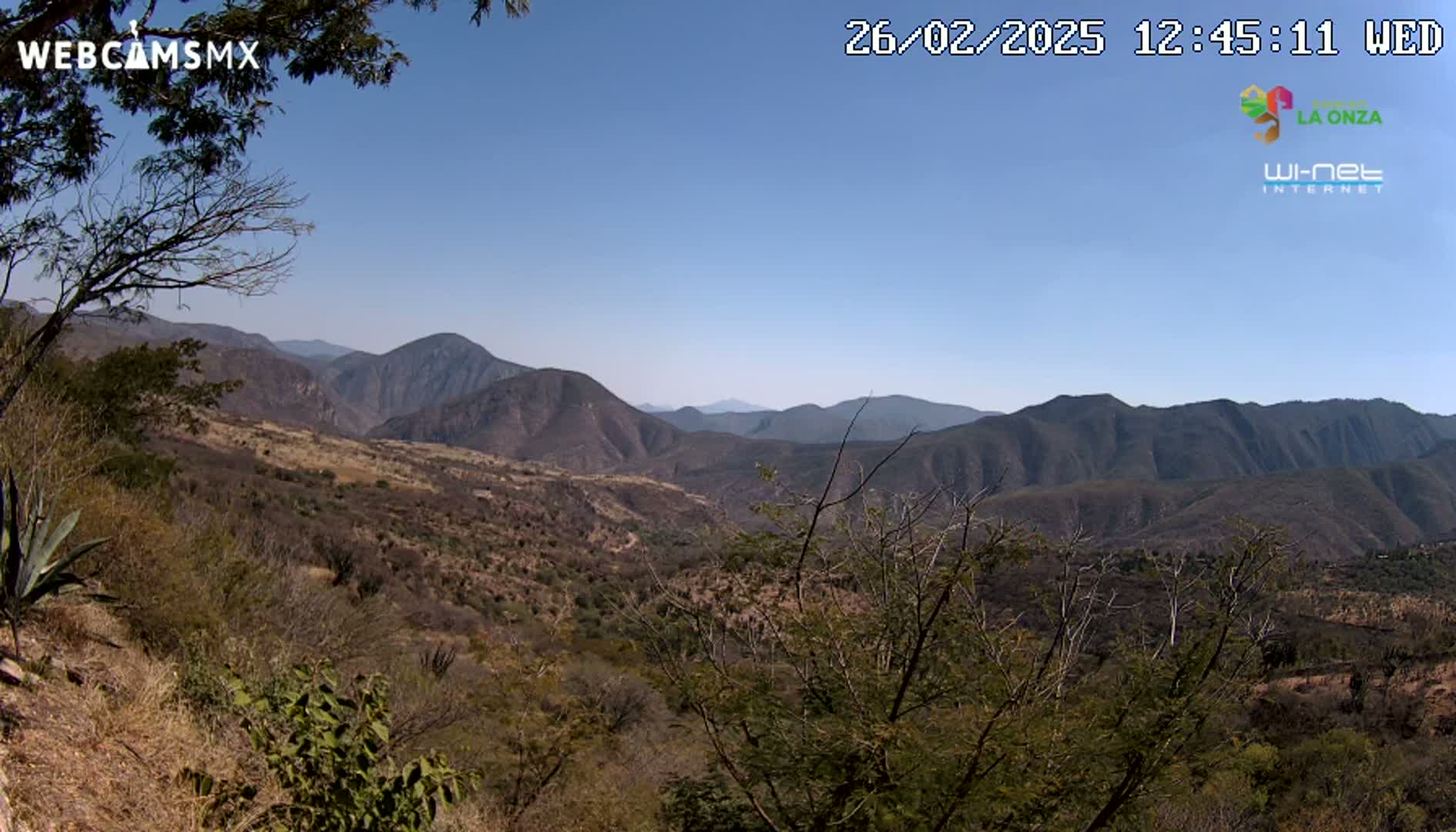 A panoramic view shows a dry, mountainous landscape under a clear blue sky.