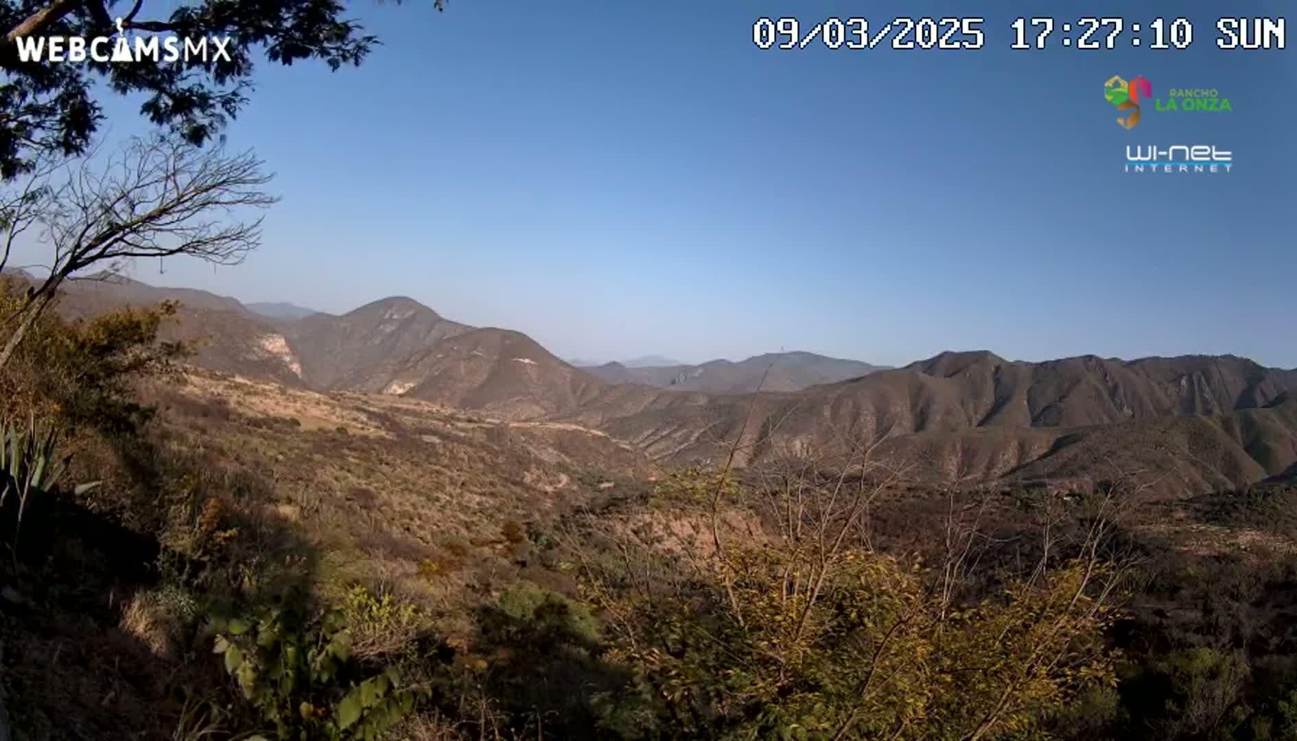 A panoramic view of a dry, mountainous landscape under a clear blue sky.