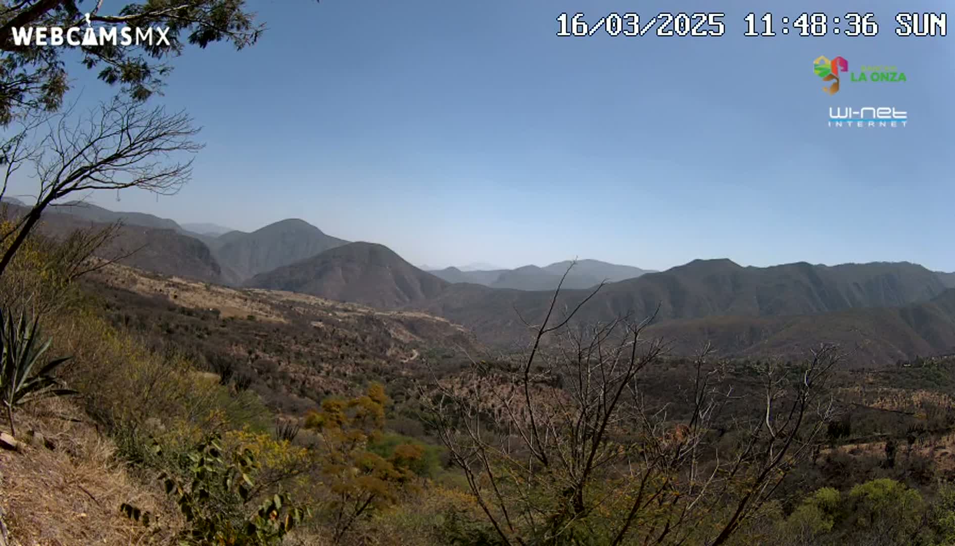 A sunny, clear day reveals a vast mountainous landscape with dry, scrubby vegetation.