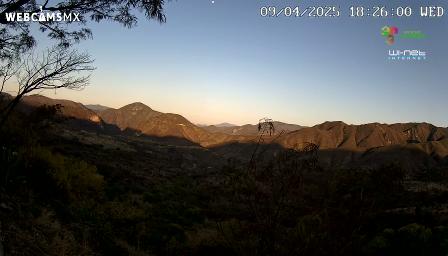 A mountainous landscape is visible at sunset under a clear sky.