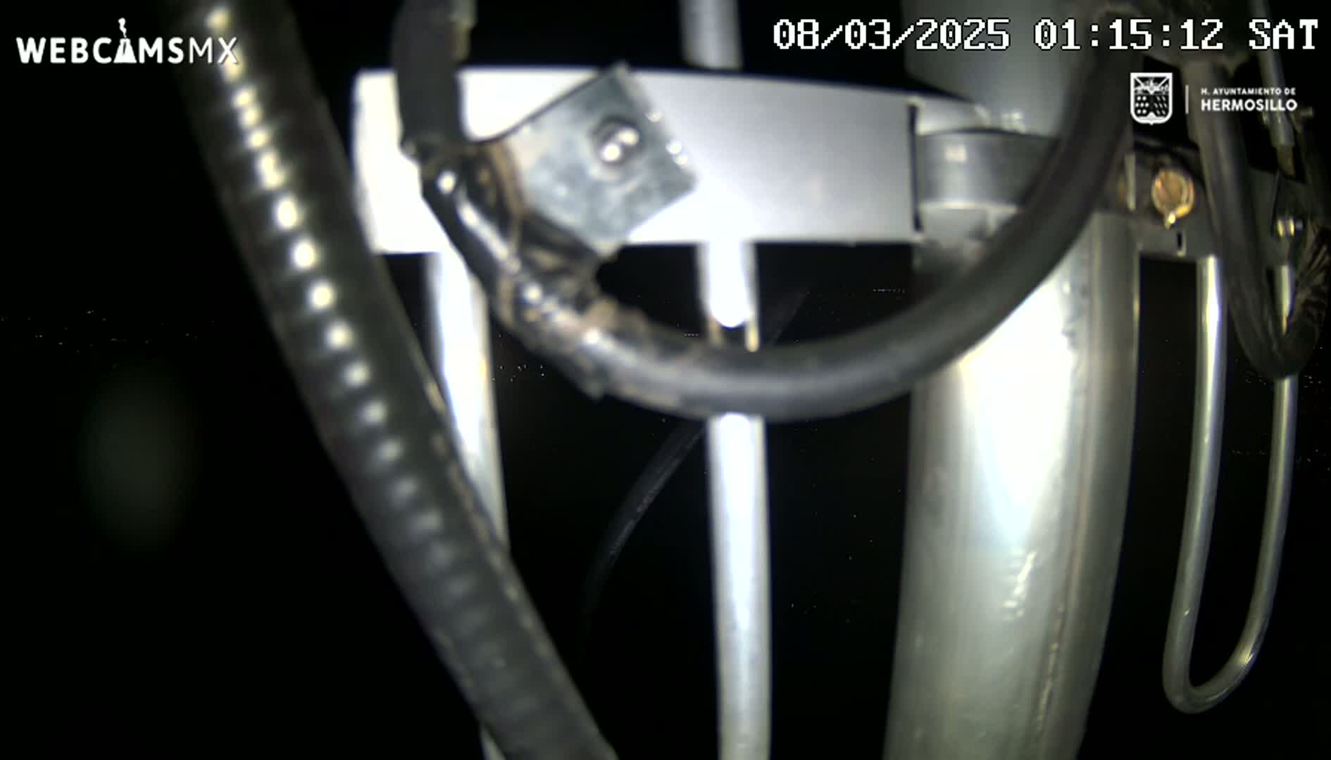 A close-up nighttime view of metallic poles and black cables against a dark background.