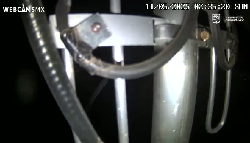 A close-up nighttime shot shows a metallic pole with various attachments and wiring.
