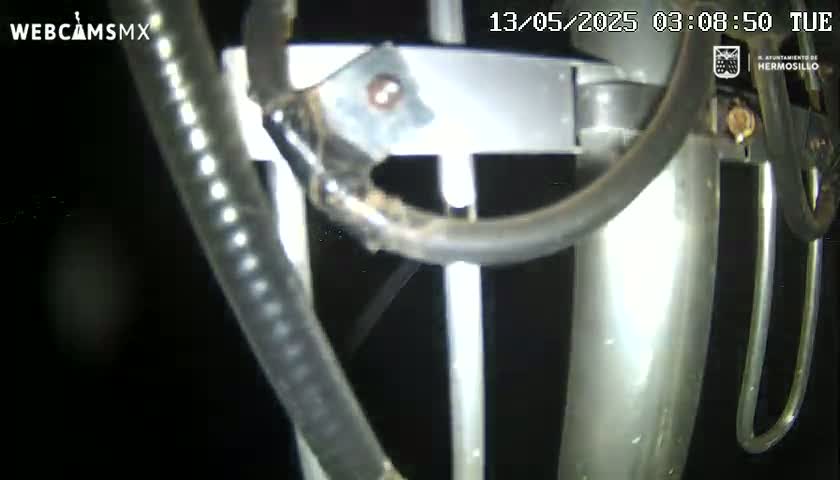 A close-up view of metallic poles and tubes, possibly part of an antenna system, at night.